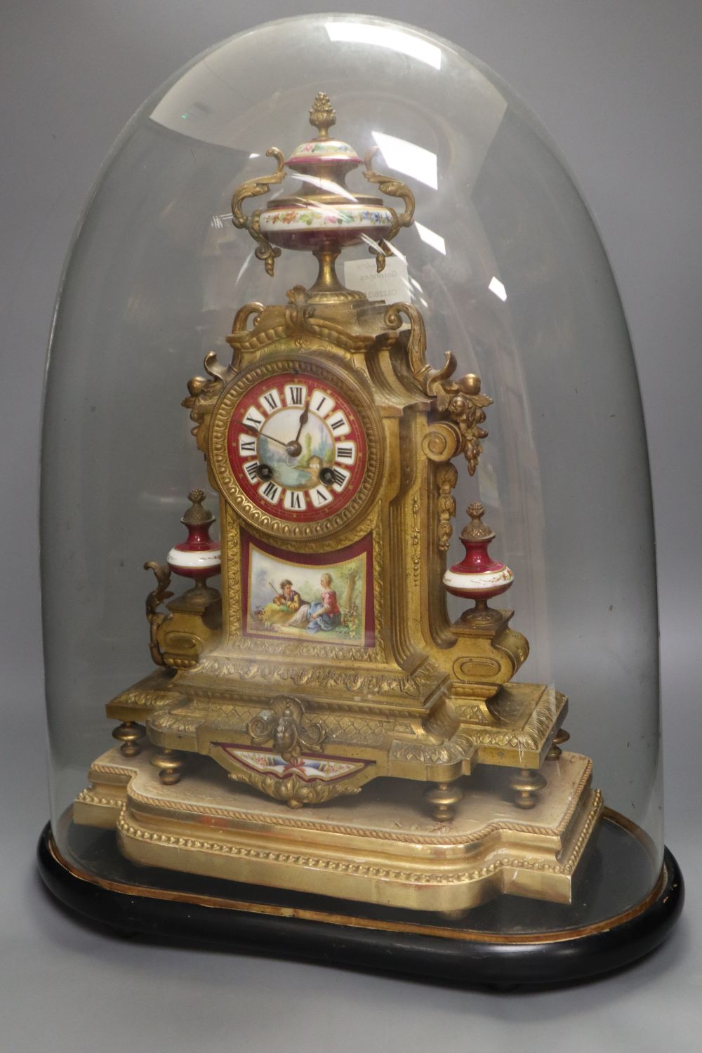 A 19th century French Louis XV style gilt spelter and porcelain mounted eight day mantel clock, on plinth, under a glass dome, with pen